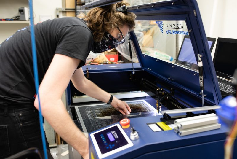 A researcher lays out a plastic sheet in a 3-D printer in a lab space.