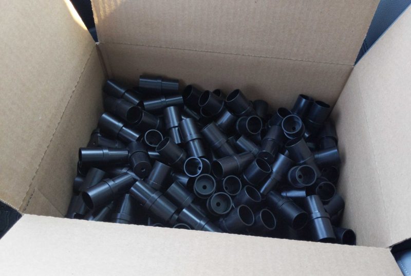 A box of nearly 200 black 3-D printed plastic connectors.