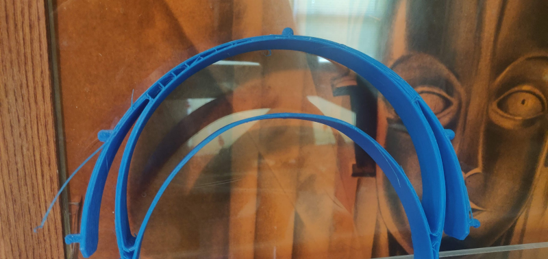 The view from above looks down at a blue 3-d printed headband with a small printing defect on the side.