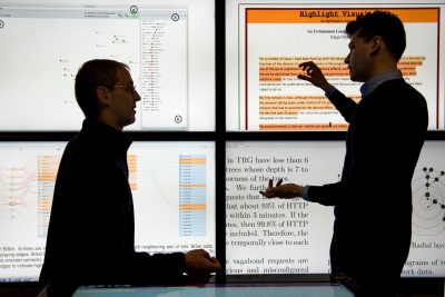 people discussing research in front of screens