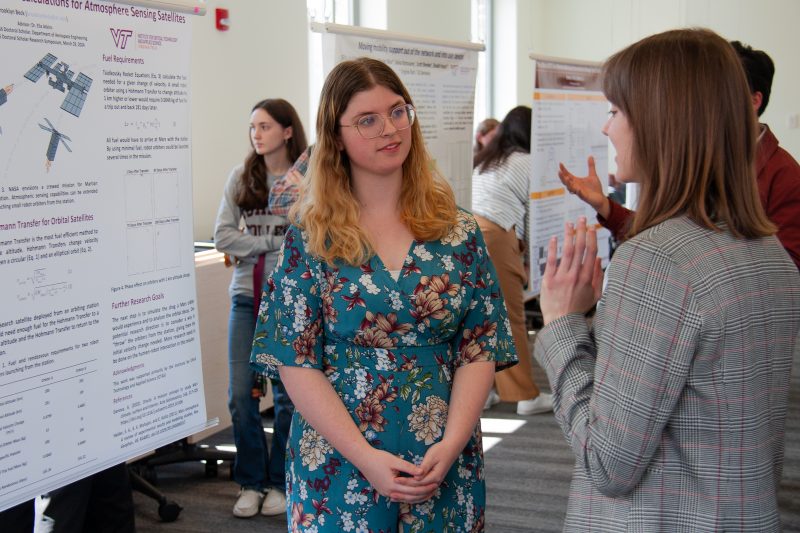 Student stands in front of poster and explains research project